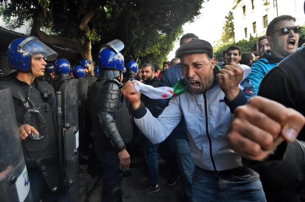 متظاهر يصرخ في وجه الشرطة خلال احتجاجات واسعة في العاصمة الجزائرية - (أ ف ب)