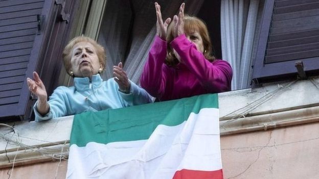  امرأتان تغنيان من النافذة، ضمن حشد من الجيران في العاصمة الإيطالية روما 